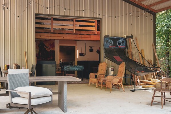 A rustic interior with a lofted sleeping area, a dining table, wicker chairs, and a television.