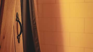 A wooden cabinet with a metal handle, a black curtain, and a white tiled wall.