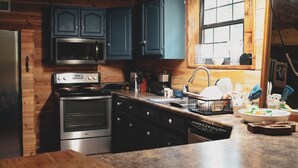 Una cocina con paredes de madera, un horno de acero inoxidable, un microondas y armarios azul oscuro.
