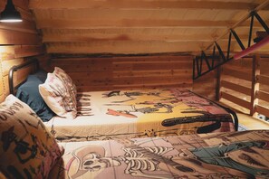 A cabin-style room with a bunk bed, wooden walls, and a sloped ceiling.
