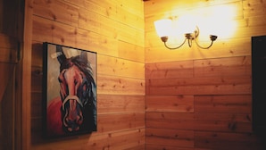 Una pared de madera con un cuadro de un caballo y una lámpara de pared.