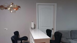 A small, modern living space with a white kitchenette, a grey sofa, and a wooden stool. - Charming, private house minutes from PADRE ISLAND  Corpus Christi. 2 full baths (Corpus Christi)
