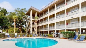 Un hôtel à plusieurs étages doté d'un espace piscine, comprenant des chaises longues et un panneau indiquant l'absence de sauveteur.