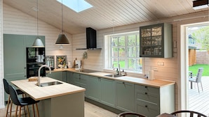 A modern kitchen with a large island, wooden cabinets, and a view of the backyard.