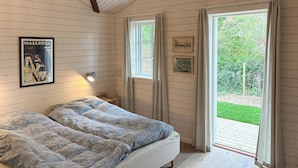 A bedroom with a bed, two windows, and a wall-mounted light fixture.