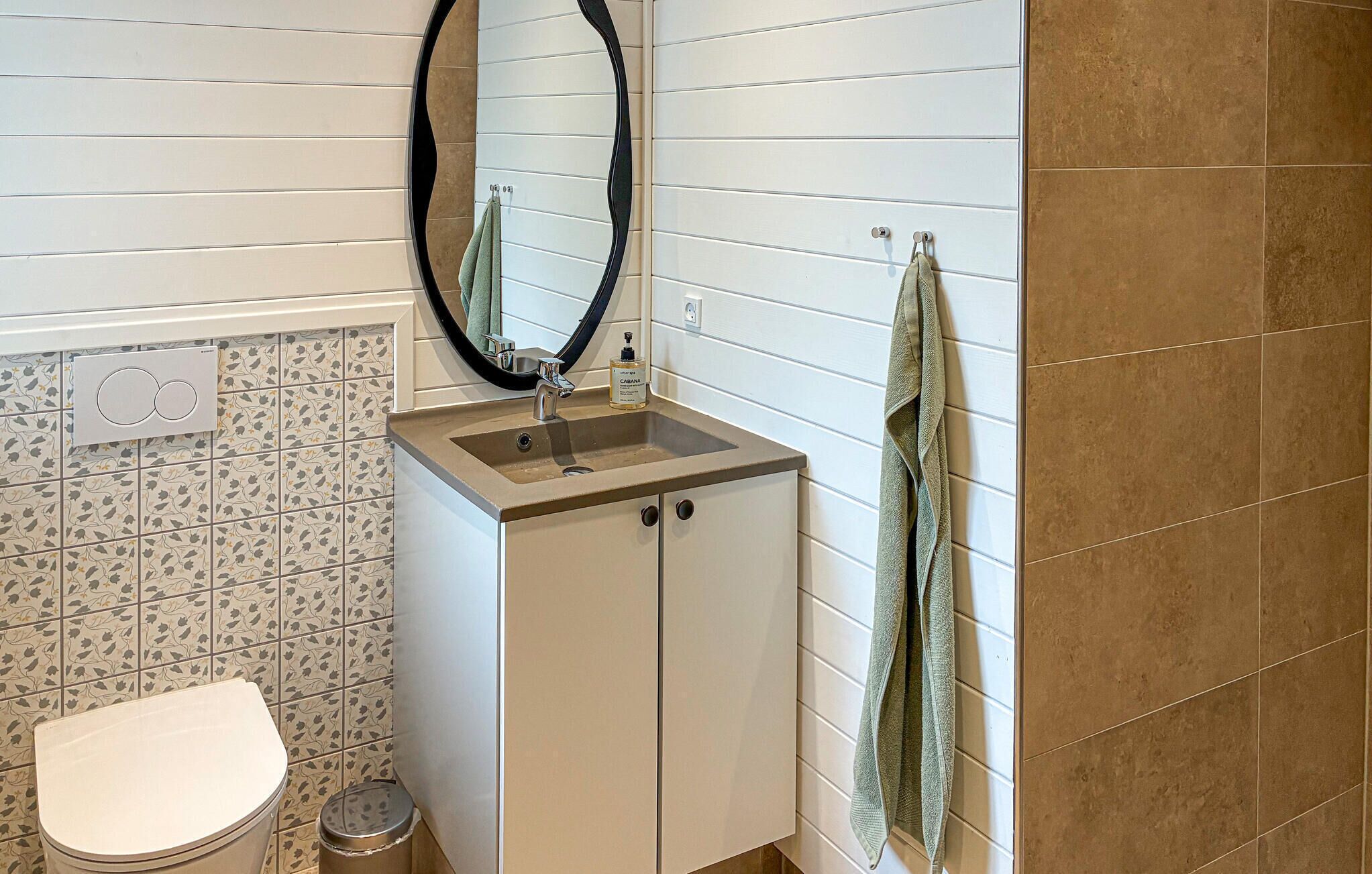 Une salle de bain avec des toilettes, un lavabo avec un miroir et une serviette accrochée au mur.