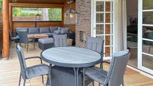 An outdoor patio with a round table and chairs, a sofa, and a brick wall.