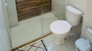 A bathroom with a shower, toilet, and a wooden accent wall. - Apartment in Salvador in the best location. (Salvador)