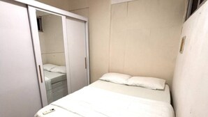 A small, white, single-bed room with a wardrobe and a mirror. - Apartment in Salvador in the best location. (Salvador)