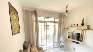 A living room with a sofa, a TV, and a balcony with a view. - Apartment in Salvador in the best location. (Salvador)