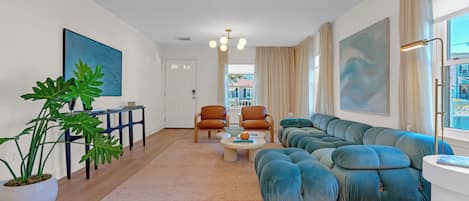 Un salon moderne avec un canapé d’angle, deux fauteuils, une table basse et une plante en pot.