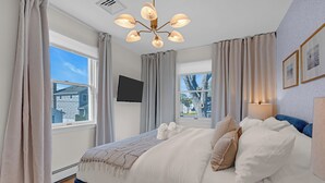 A modern bedroom with a large bed, two windows, a flat-screen TV, and a chandelier. - Prof Cleaned | Linens+Towels | Fast WIFI | Coffee (Lake Como)