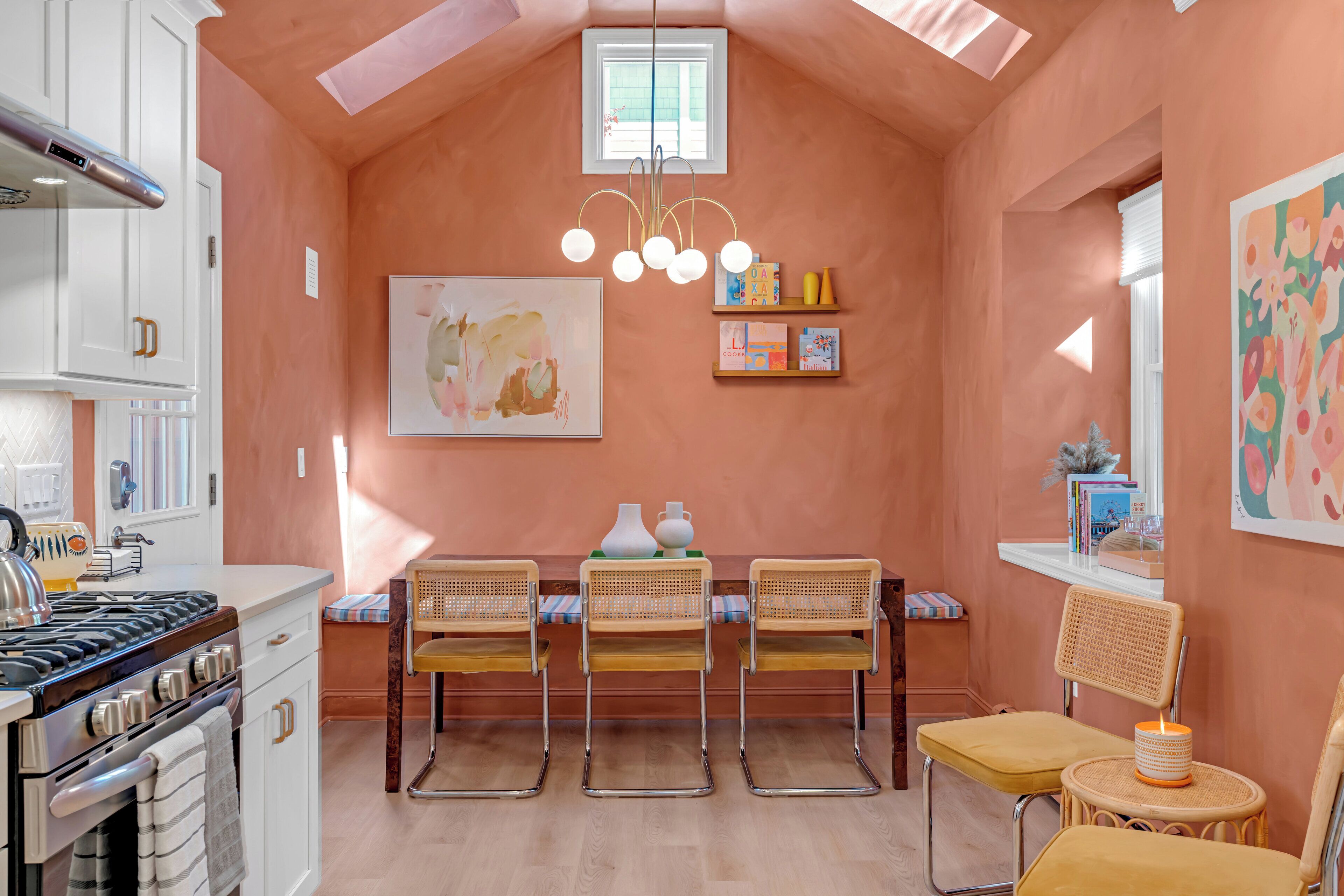 A kitchen with a gas stove, white cabinets, and a dining area with chairs and a table.