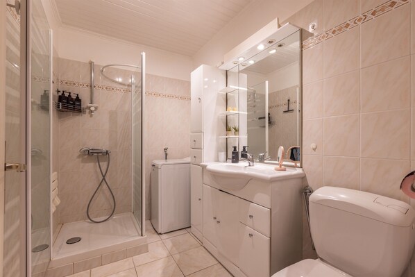 A modern bathroom with a glass-enclosed shower, a white sink with a mirror above, and a toilet.