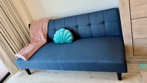 Een blauwe bank met een roze plaid en een turquoise kussen.