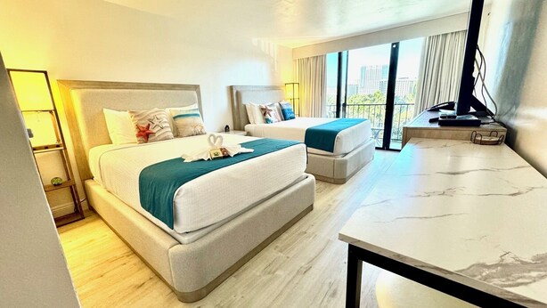 Hotelkamer met een groot bed, een kleiner bed, een bureau en uitzicht op de stad.