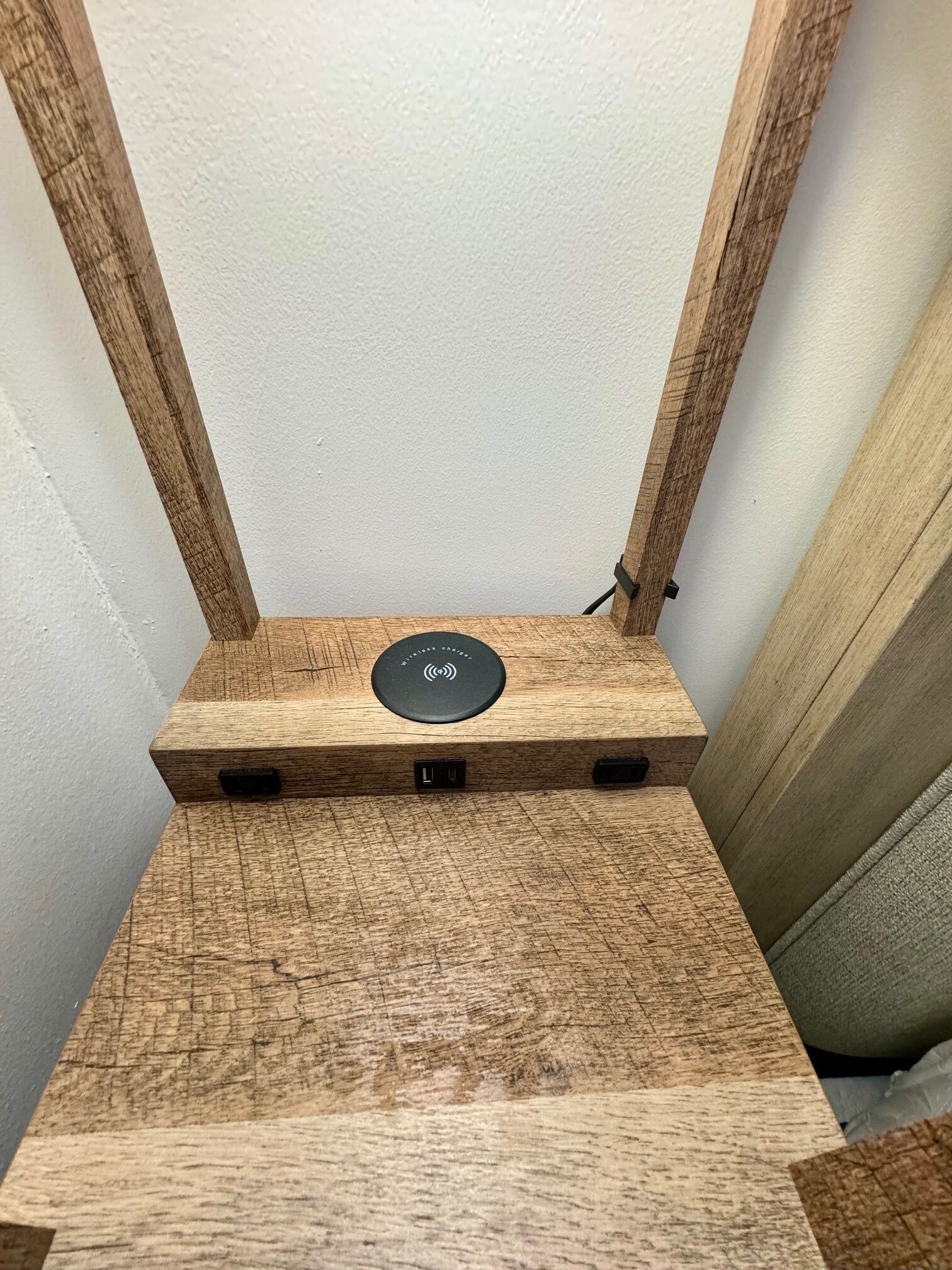 Un altavoz de madera con un panel de control circular, colocado contra una pared blanca.