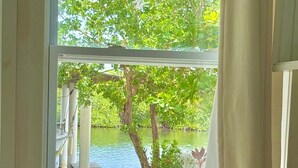 A kitchen with a window view of a garden and water body. - Utila Seabreeze Vacation Apartments (Isla de Utila)