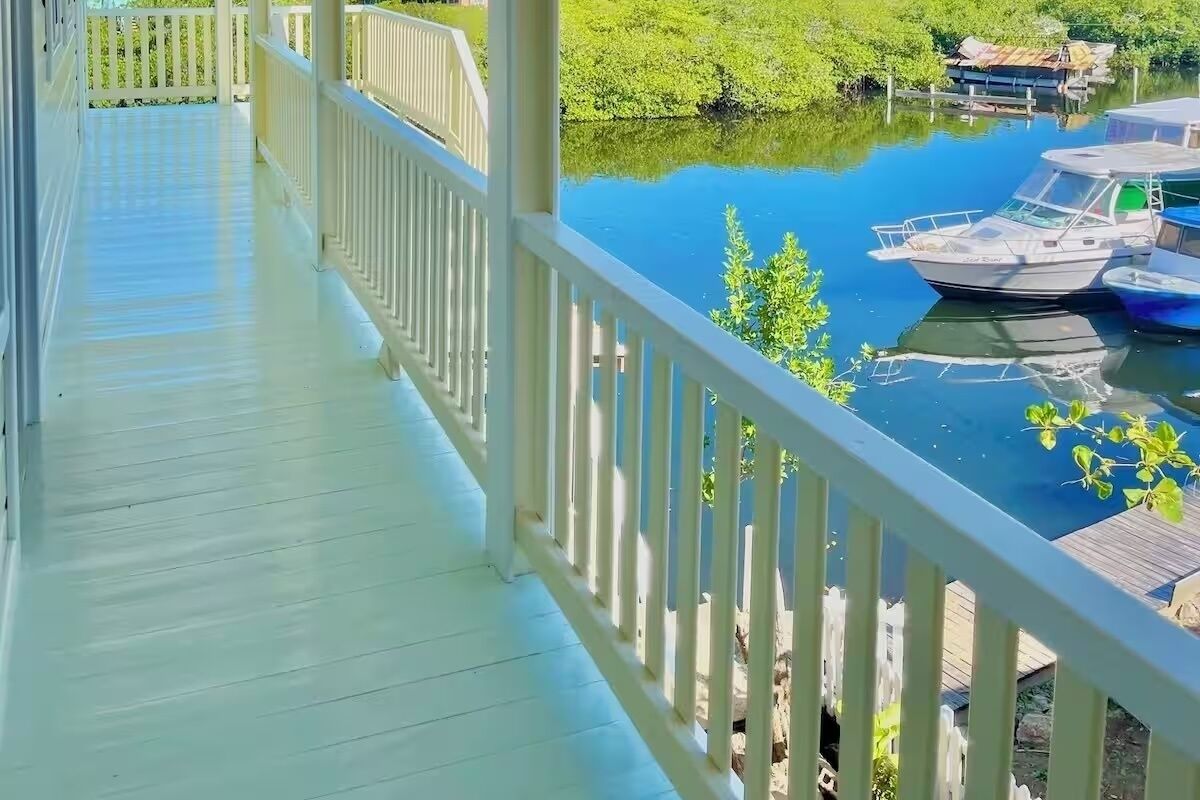 A wooden deck with a railing overlooking a calm body of water with boats.