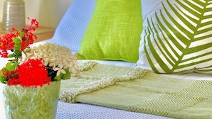A room with a bed, a green pillow, a green throw blanket, and a vase with flowers. - Utila Seabreeze Vacation Apartments (Isla de Utila)