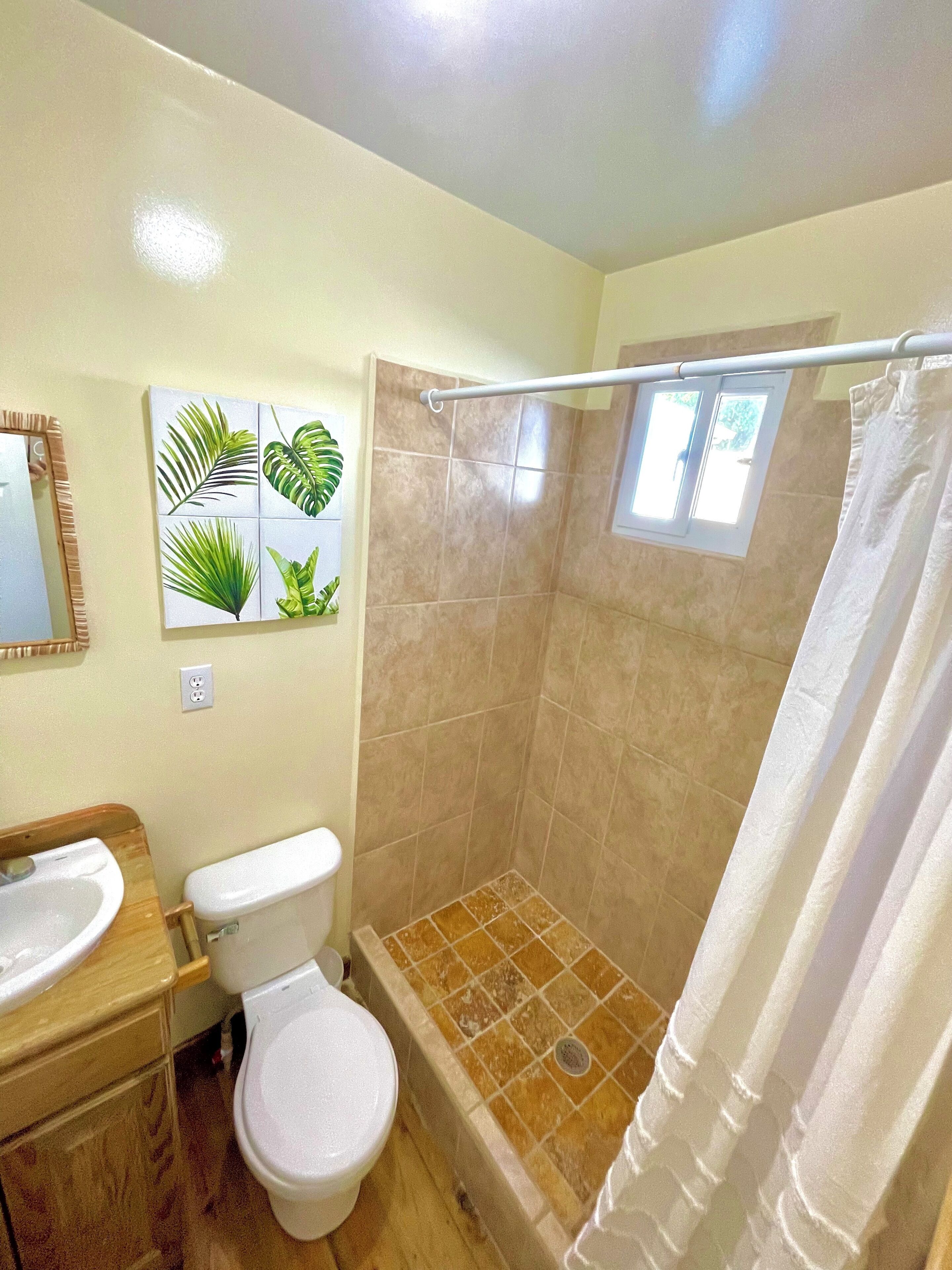 A bathroom with a shower, toilet, and sink.