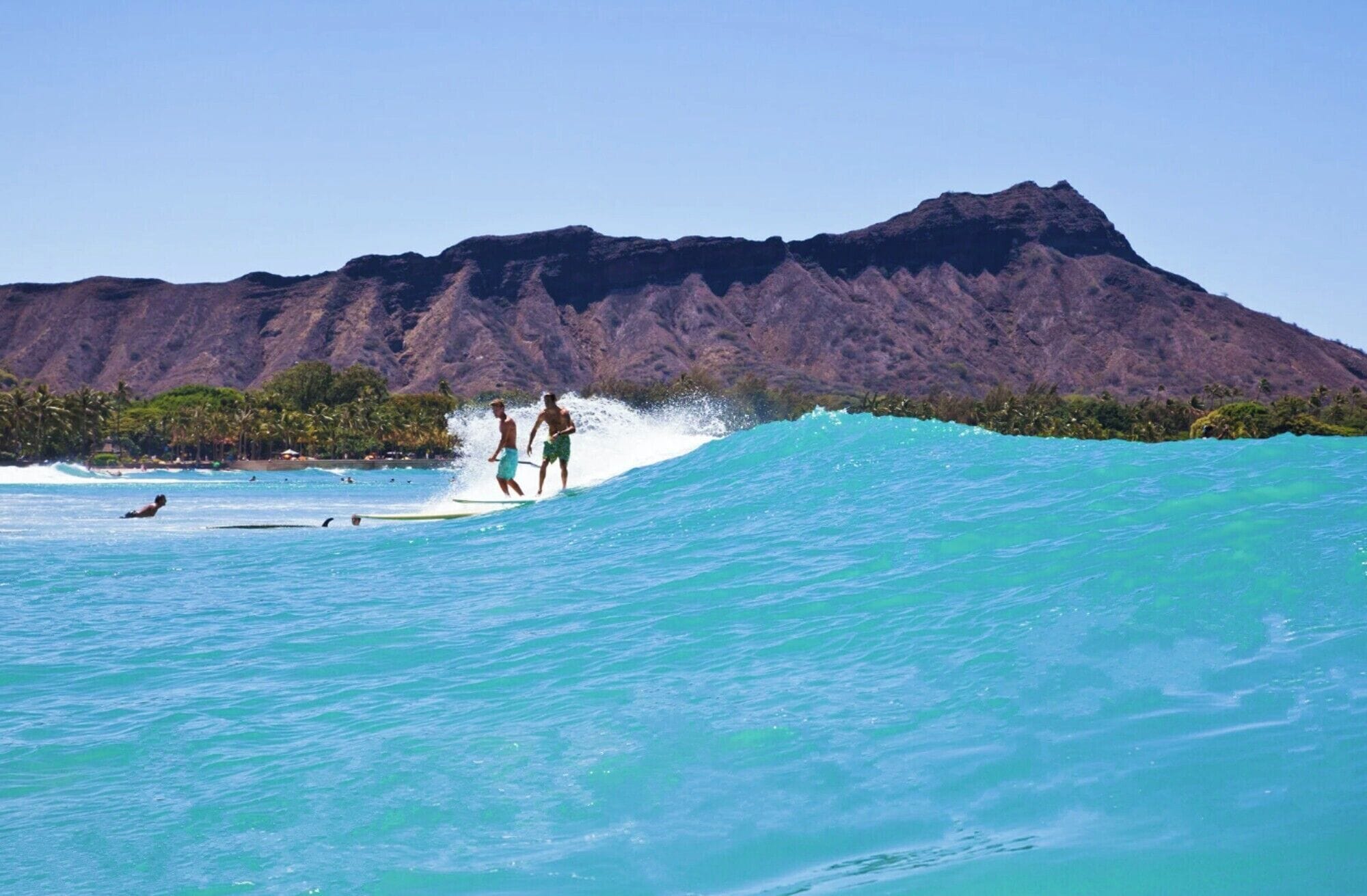 A beach with surfers and a mountain in the background.