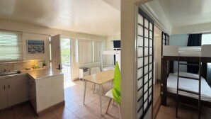 Habitación de hotel compacta con literas, kitchenette, comedor y vistas al exterior.