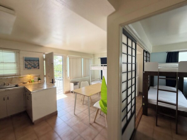A compact hotel room with bunk beds, a kitchenette, a dining area, and a view of the outdoors. - Bposhtels Waikiki Retreat (Honolulu)