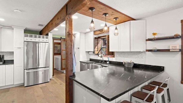 Una cocina moderna con una isla central, electrodomésticos de acero inoxidable y vigas de madera.