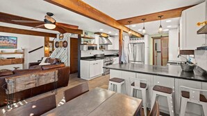 Una cocina moderna con armarios blancos, una isla central y taburetes de bar.