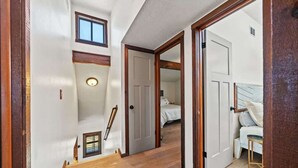 Una escalera que lleva a un dormitorio con una cama, una mesita y una silla.