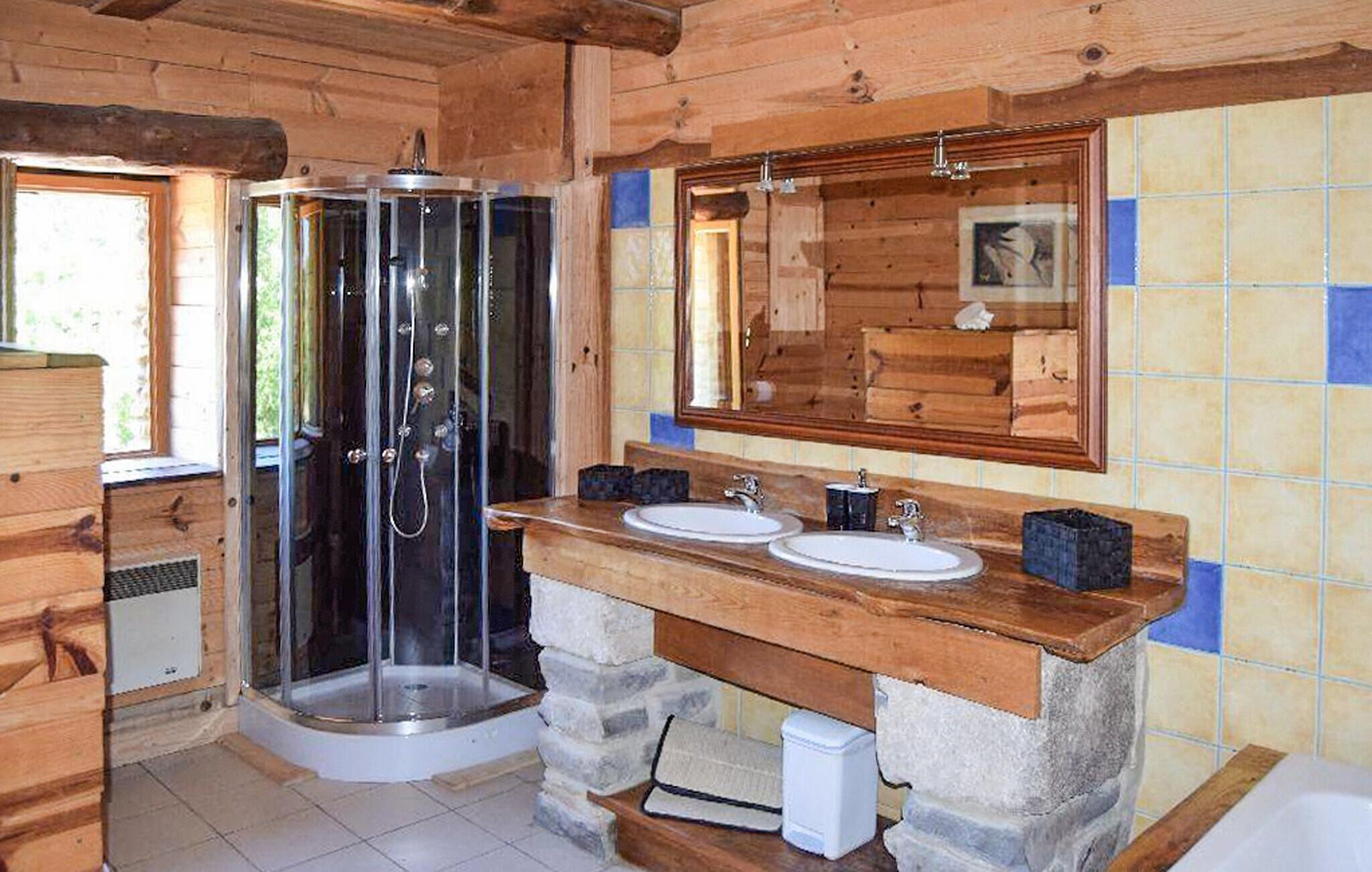 Bany d'una cabana de fusta amb plat de dutxa de vidre, dues rentadores i un mirall gran.