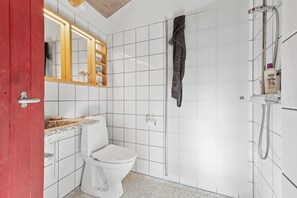 A bathroom with a white toilet, a shower, a mirror, and a towel hanging on the wall.