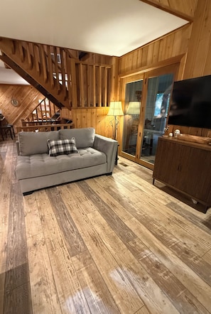 A cozy living room with a sofa, a television, and wooden flooring.