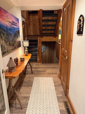 A wooden staircase with a view of the outdoors, a desk with a lamp, and a rug on the floor.