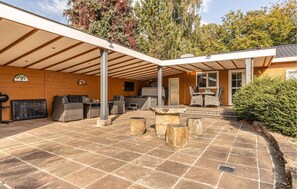 A covered patio with stone flooring, outdoor seating, and a grill area. - 3 bedroom stunning home in Erm (Erm)