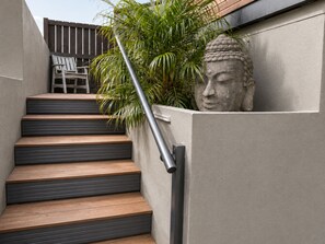 Holzstufen führen zu einer Betonmauer mit Metallhandlauf.