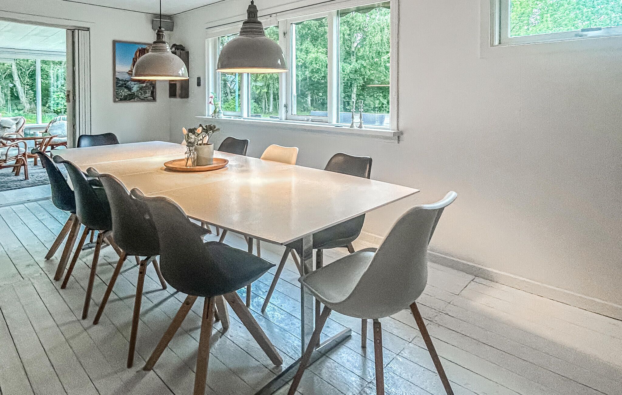 Comedor con una mesa grande, sillas, lámparas colgantes y ventanas amplias.