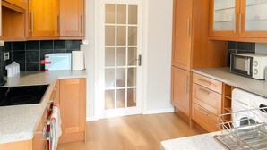 A kitchen with wooden cabinets, a microwave, a toaster, and a sink. - Charming 3-bedroom house in Sittingbourne for contractors, family & Tourists!! (Sittingbourne)