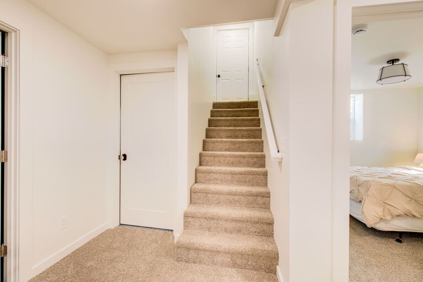 A staircase leading to a bedroom with a bed and a nightstand.