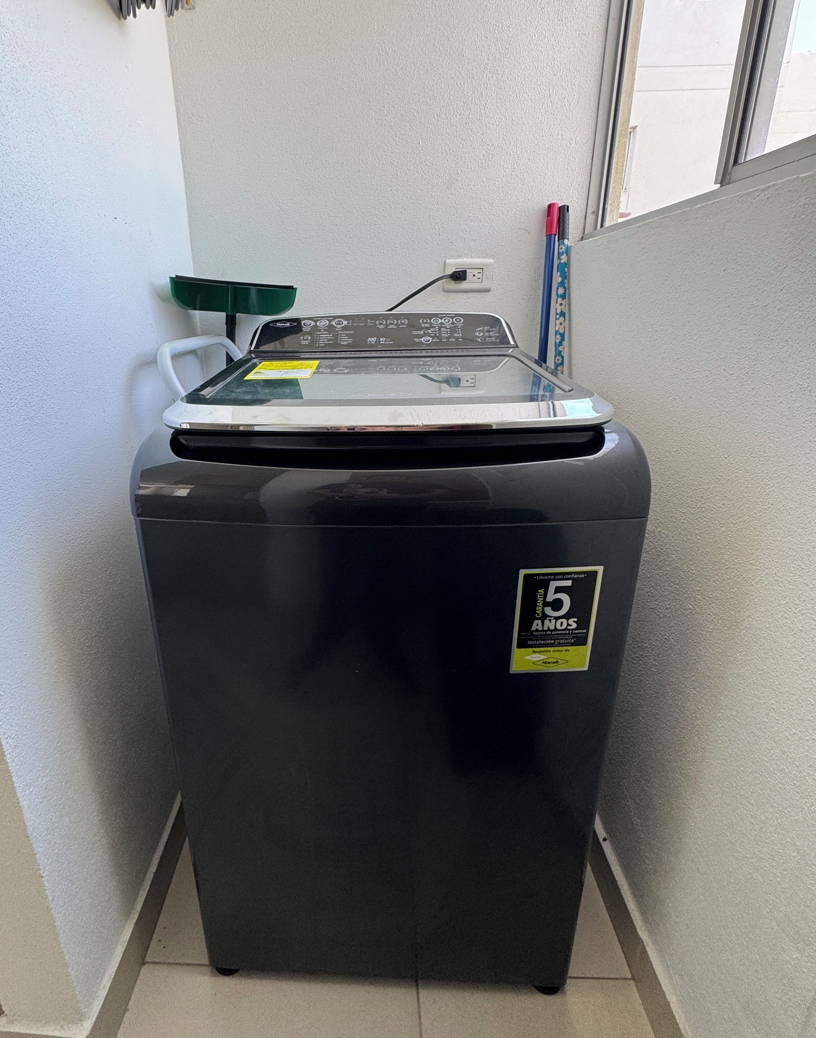 En liten, svart tvättmaskin med en kontrollpanel och en etikett som anger en 5-års garanti.
