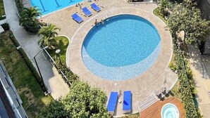 A swimming pool area with a rectangular pool, a circular pool, and a small wooden pool. There are lounge chairs and a building with a roof. - Santa Marta - pozos colorados playa (Santa Marta)