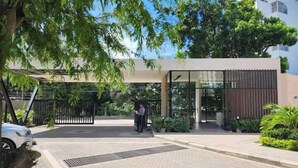 A modern building entrance with a glass door, a paved driveway, and a security gate. - Santa Marta - pozos colorados playa (Santa Marta)