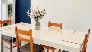 Un'area pranzo moderna con un tavolo bianco, sedie in legno e un vaso di fiori.