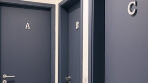 Tre porte scure con le scritte A, B e C in un corridoio con pavimento chiaro.