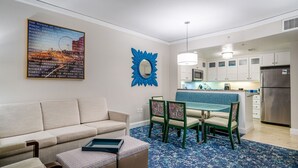 A modern living room with a sofa, a dining table with chairs, a kitchen with white cabinets, and a blue patterned rug. - 2-bedroom resort in delightful Myrtle Beach with AC, fitness room (Myrtle Beach)
