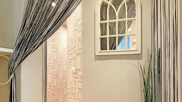 A hallway with patterned wallpaper, a window with a view, and a potted plant. - Once upon a time - Cozy and familiar house next to the Cathedral Burgos (Burgos)