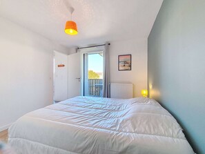 Une chambre à coucher avec un lit, une porte, une fenêtre et un tableau au mur.