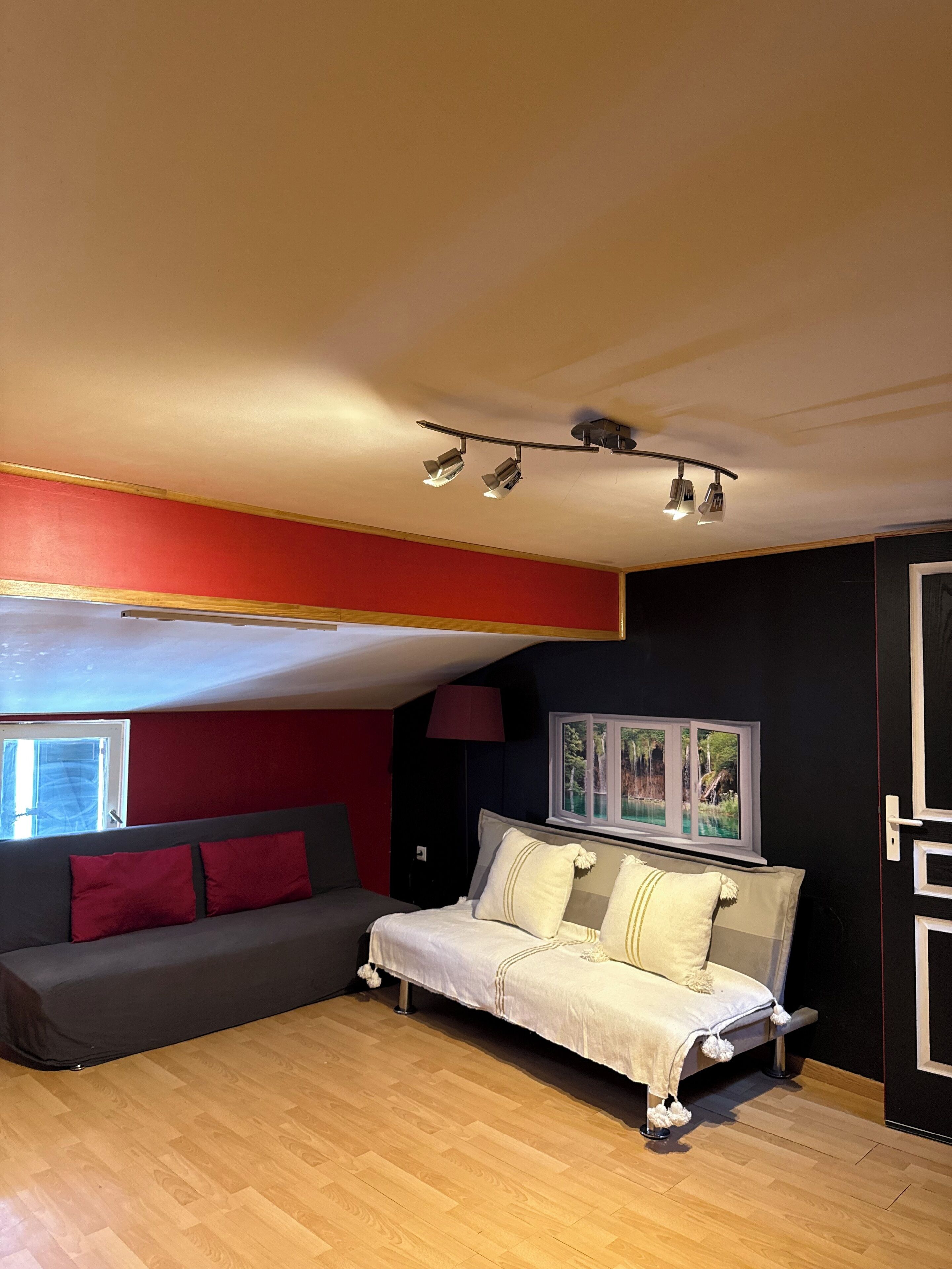 Een slaapkamer met een bed, een bank, een raam en een plafondlamp.