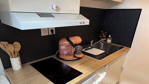 A compact kitchen with a built-in oven, a coffee maker, and a sink. - The little cocoon (Vierzon)